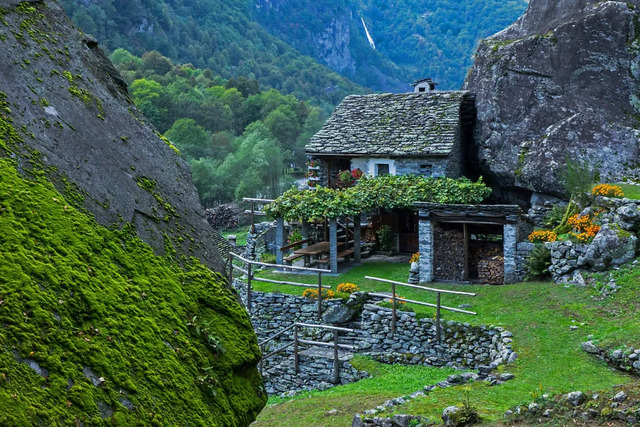 The alleyways are often lined with flowers and greenery, softening the rugged stone exteriors and adding a touch of color to the muted tones of the buildings