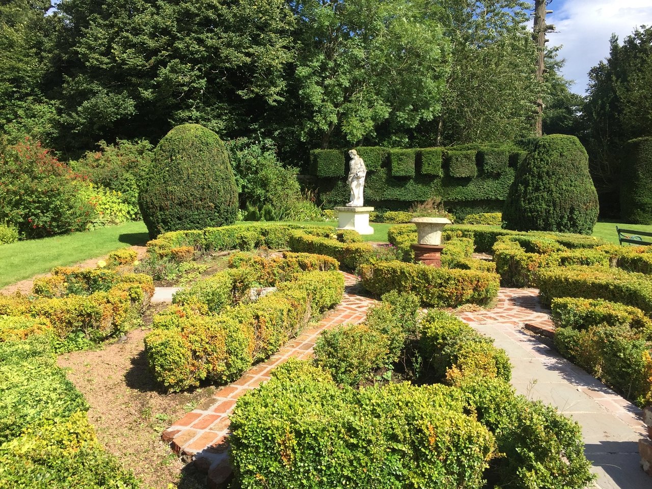 The gardens are adorned with classical statues and intricately shaped topiary that lend a sense of grandeur and symmetry to the space