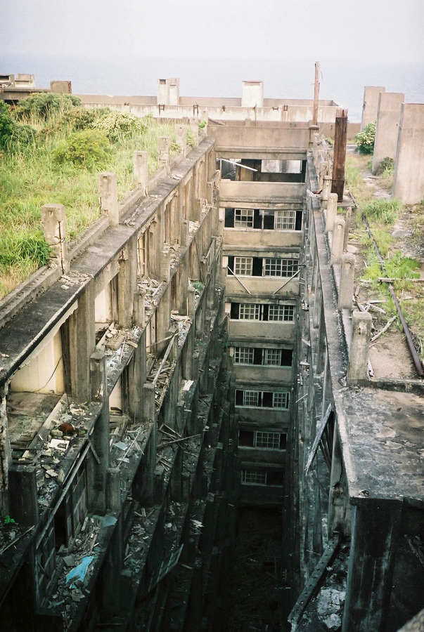 The towering structures of Hashima created a labyrinth of narrow, shadowy streets.