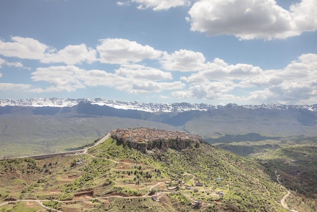 A breathtaking view of the City of Amadiyah perched atop a mountain plateau in northern Iraq, surrounded by lush greenery and majestic mountains