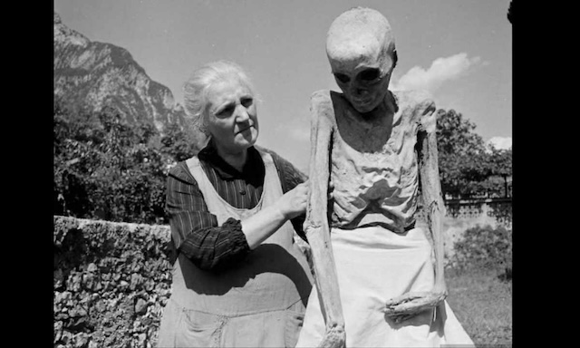 A woman from Venzone carefully tends to a centuries-old mummy, a unique tradition where locals maintain close relationships with these preserved ancestors