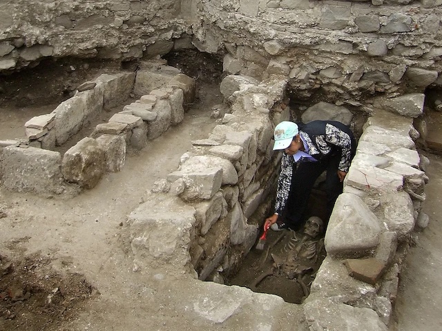 An archaeologist carefully excavates the skeleton of the "Toothless Vampire" in Sozopol, revealing the detailed stone grave and burial context