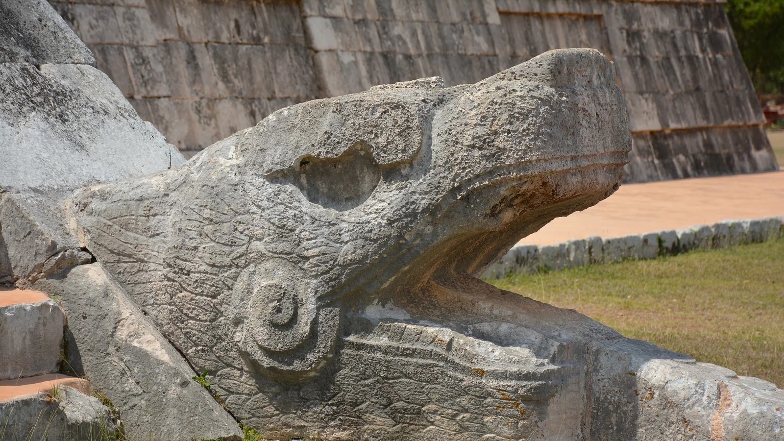 The detailed serpent head sculpture at the base of the Kukulcan Temple, symbolizing the Feathered Serpent God, central to Maya mythology