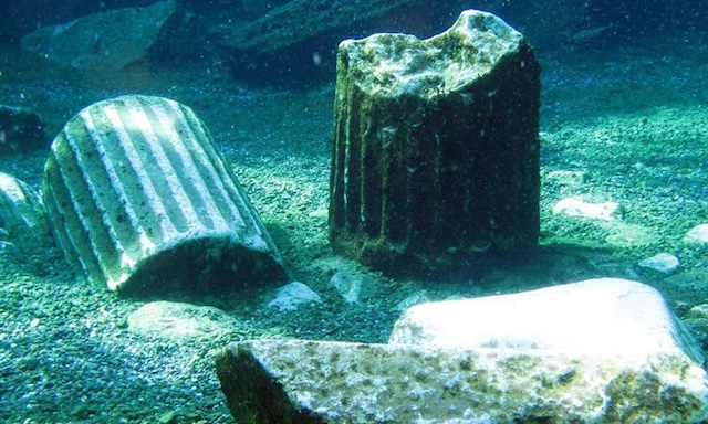 Marble columns and ancient structures submerged in the clear, warm waters of Cleopatra's Pool, a testament to the historical earthquake that shaped the pool's unique layout