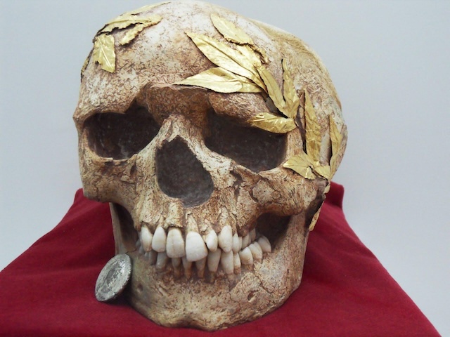 Close-up of the same skull, with a silver coin found in its mouth, believed to be a token for Charon, the ferryman to the underworld in Greek mythology