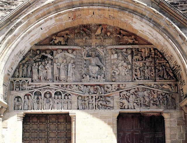 The grand tympanum of the Abbey of Sainte Foy, adorned with detailed carvings depicting religious scenes, including the hidden gem of "The Peeker.