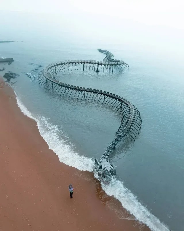 The monumental sea serpent sculpture appearing to slither through the water, captivating visitors with its lifelike form and massive scale