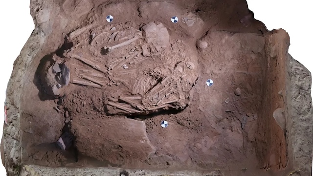 An overhead shot of a burial in the Nenggiri caves, highlighting the intricate arrangement of bones and surrounding artifacts, offering insights into ancient burial practices