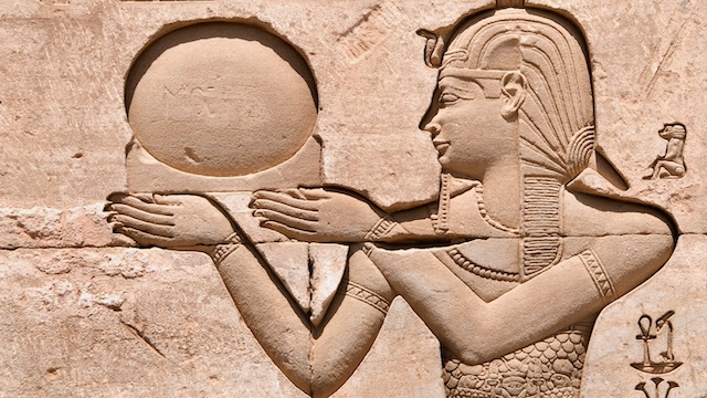 A relief sculpture of an Egyptian figure holding the sun disk, symbolizing the significance of Egyptian religious and cultural practices during Cleopatra's reign