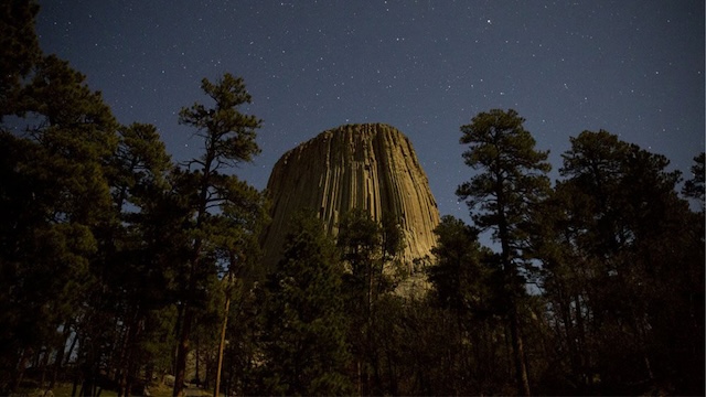 The silhouette of Devils Tower under a starry night sky adds to the monument’s enduring allure and sense of mystery