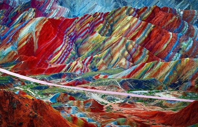 The vivid stripes of the Danxia mountains are beautifully highlighted against the rugged terrain, offering a dramatic and unforgettable scene in the Chinese landscape