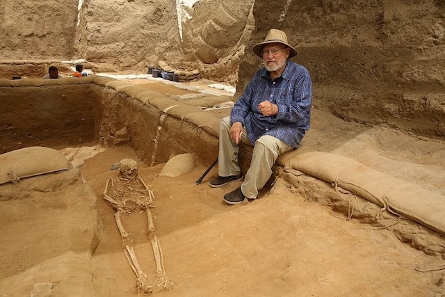 A researcher sits near a Philistine burial as part of an extensive archaeological excavation in the region of Philistia