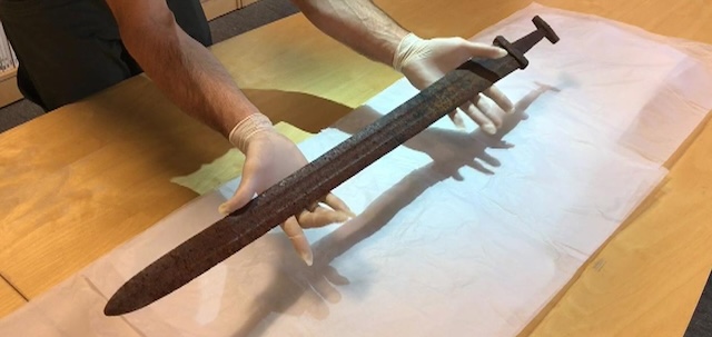 Experts carefully handle the Viking sword during its transfer to a laboratory for further examination and conservation