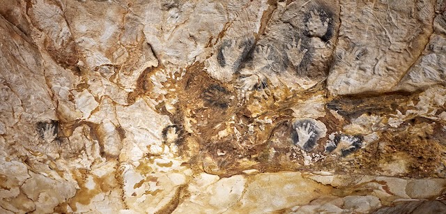 A section of the Cosquer Cave wall adorned with ancient handprints and carvings, preserved underwater for thousands of years