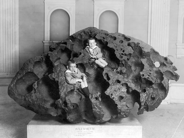 The Willamette meteorite, the largest meteorite found in the United States, with children posing on it in a historic photograph