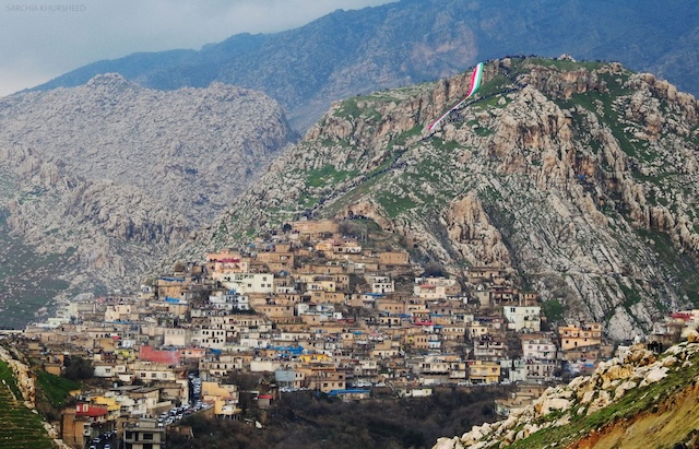 The City of Amadiyah nestled within a rugged mountainous landscape, with homes and buildings sprawling along the cliff edges