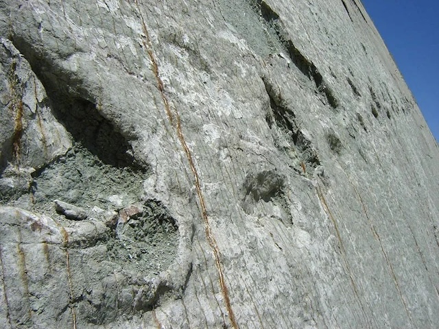 An expansive view of the vertical rock wall, where thousands of dinosaur footprints stretch up toward the sky