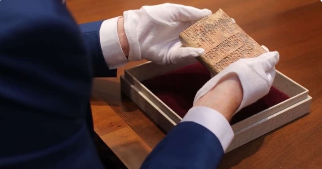 Dr. Daniel Mansfield carefully examining the ancient clay tablet, a key to understanding the advanced mathematical knowledge of the Babylonians