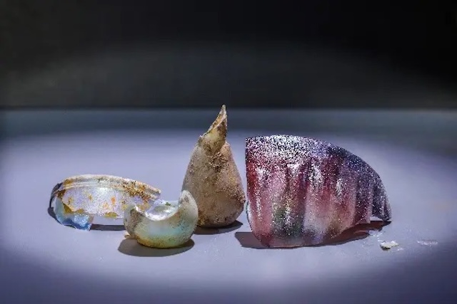 A collection of ancient glass shards and pottery pieces from the same period, giving a glimpse into craftsmanship techniques of the time