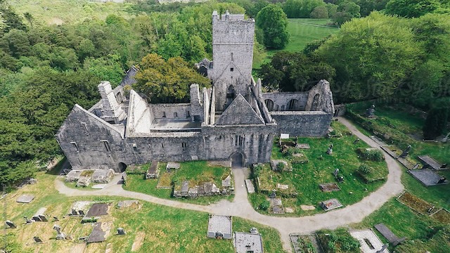 An aerial view of Muckross Abbey, showcasing its beautifully preserved ruins amidst the lush greenery of Killarney National Park