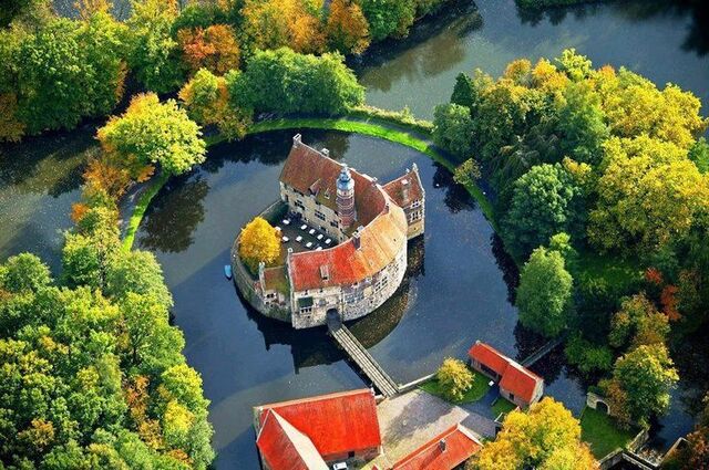 A breathtaking view of Vischering Castle nestled in autumnal scenery, framed by colorful foliage.