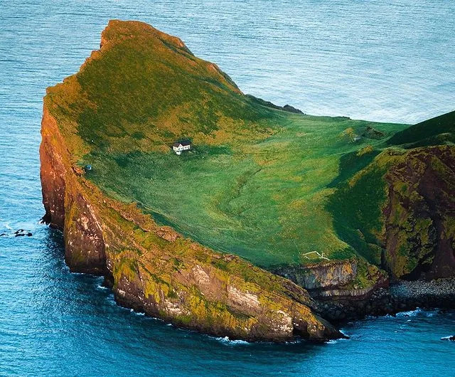 A captivating perspective of the island’s dramatic cliffs and the house nestled within.