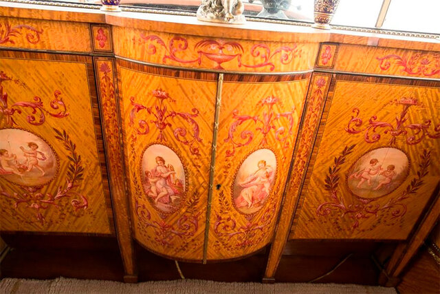 A close-up of the wooden cabinetry, intricately designed with painted motifs, reflecting the regal aesthetic of the 1926 Rolls Royce.