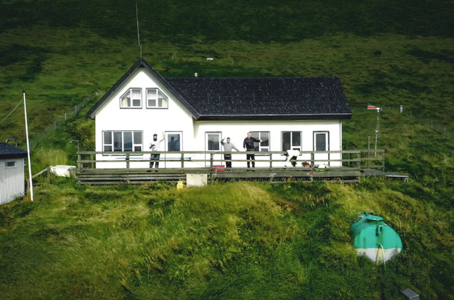 A closer view of the house with visitors, highlighting its serene and remote allure.