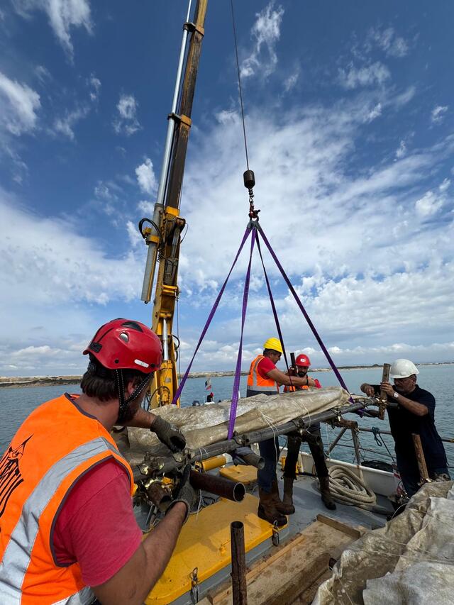 A crane raises preserved orichalcum ingots, believed to have originated from ancient Greece or Asia Minor, from the sea.