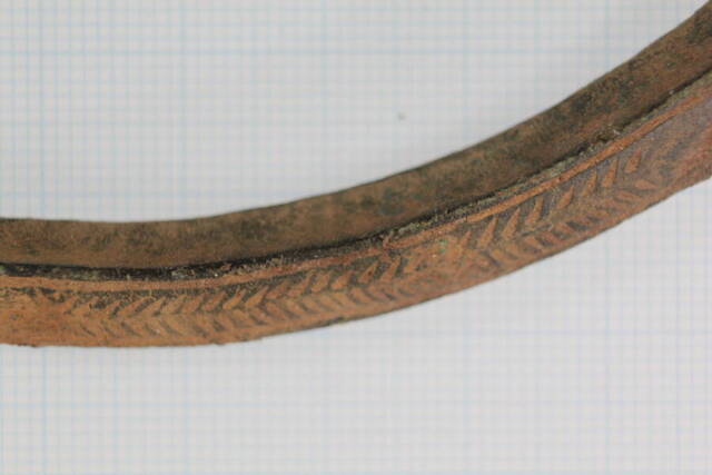 A detailed close-up reveals the intricate design and artistry of the ancient neck ring.