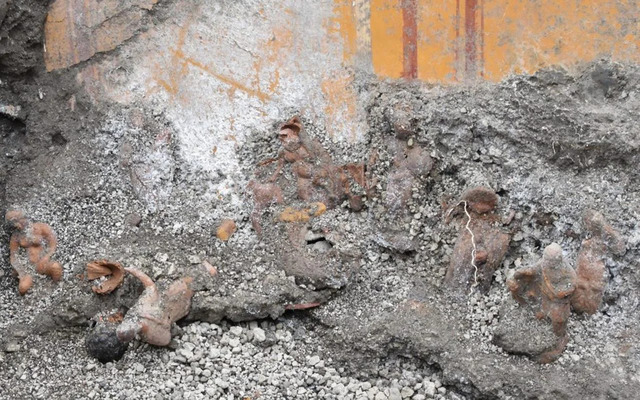 A detailed view of terracotta figurines embedded in the volcanic ash layer, offering a glimpse of their initial discovery site during the archaeological excavation.