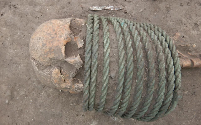 A detailed view of the woman’s burial, showcasing the intricate bronze neck rings she wore.