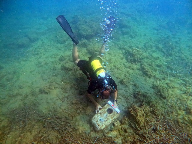 A diver inspects the stone anchor discovered alongside the shipwreck, offering insight into the ship's construction and anchoring methods.