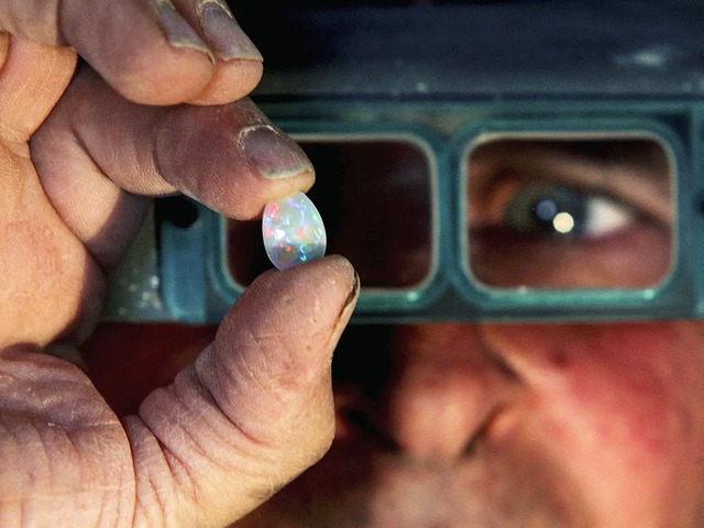 A miner proudly displays a freshly unearthed opal stone, the treasure of Coober Pedy.