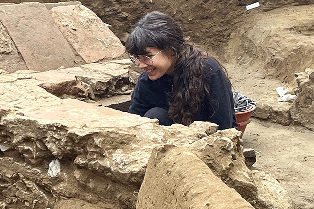 A moment of discovery as a volunteer gleefully investigates an ancient burial structure, uncovering details about medieval funerary practices.