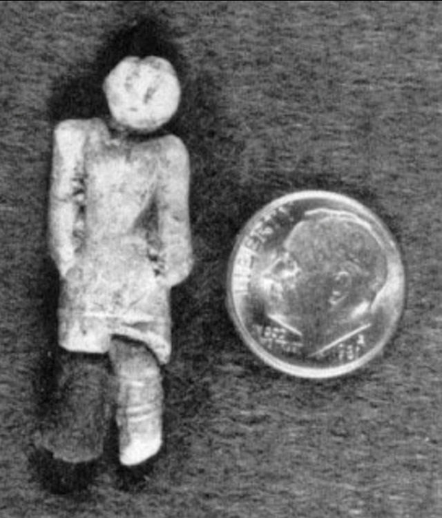 A scale view showing the small size of the figurine, placed next to a coin for perspective.