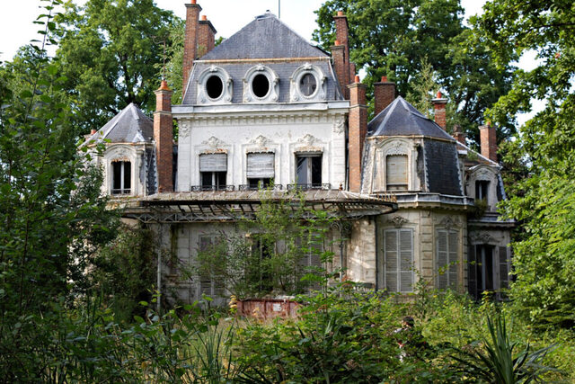 A shot highlighting the elegant dormer windows and rooftop design of the once-stately manor.