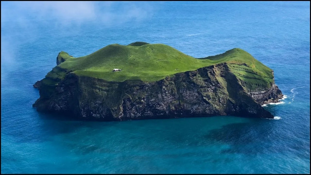 A stunning aerial view of the isolated house surrounded by the vast North Atlantic Ocean.