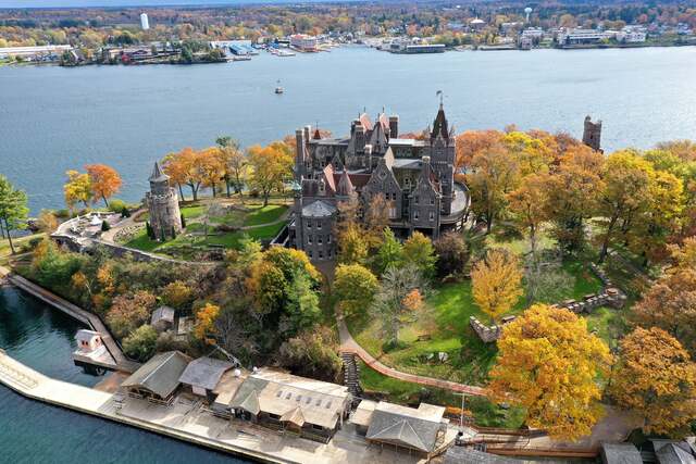 A vibrant autumn view of Heart Island, showcasing Boldt Castle amidst a palette of fall colors and the calm waters of the Thousand Islands.