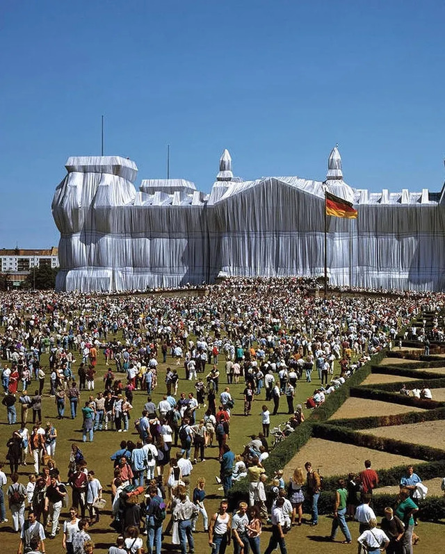 A vibrant scene showing thousands of visitors exploring the surroundings of the Wrapped Reichstag during its two-week exhibition in Berlin.