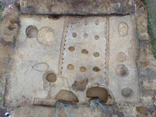 Aerial view of the longhouse site, showcasing storage pits and utility areas surrounding the structure.