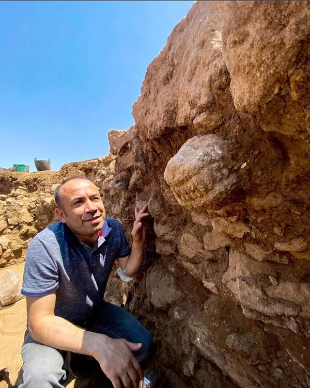 An archaeologist examining a detailed carving on the stone wall at the Gobekli Tepe site.