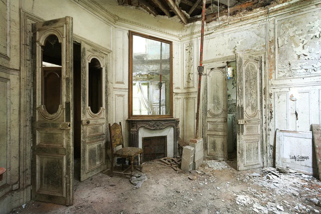 An atmospheric shot of one of the chateau’s ornate rooms, showcasing vintage fireplaces and distressed doors.