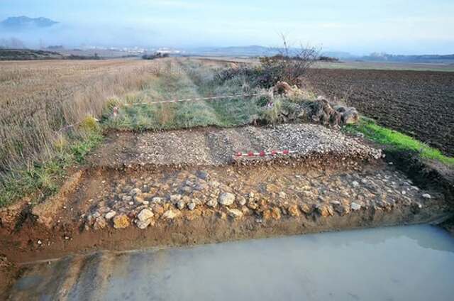 An excavated segment of a Roman road in a rural area, demonstrating the advanced engineering techniques used in various terrains.