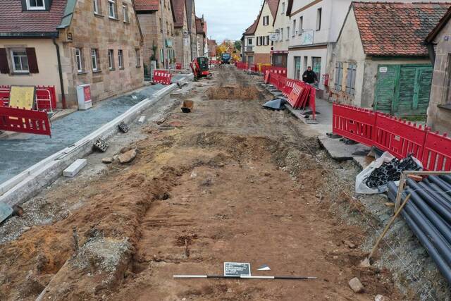 Archaeological teams and construction crews work together to preserve and study the wooden planks uncovered beneath the modern road.