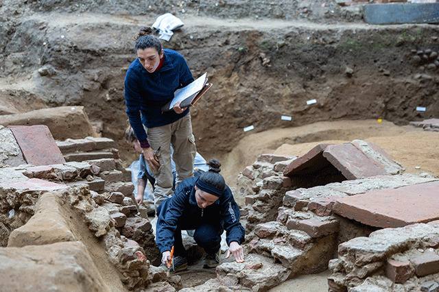 Close-up of archaeologists documenting and analyzing the intricate construction of a 7th-century Lombard royal tomb.