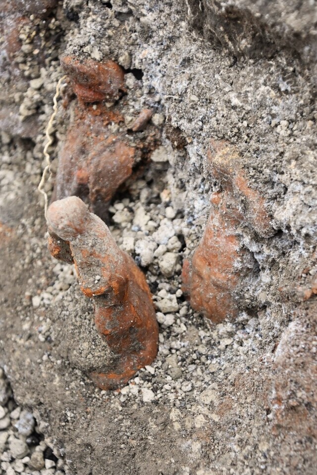 Close-up of terracotta figurines partially revealed within the ash layer, capturing the meticulous excavation process.