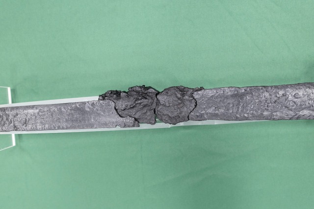 Close-up view of the blade, showing visible damage, micro-cracks, and wear that narrates its possible use in combat.