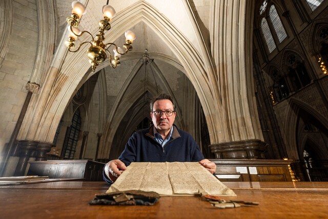 Matthew Payne, Keeper of the Muniments at Westminster Abbey, showcases the historic document with the precious silk seal bag attached.