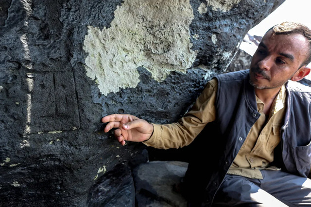 Jaime de Santana Oliveira points to one of the recently exposed rock carvings, shedding light on ancient Amazonian culture.